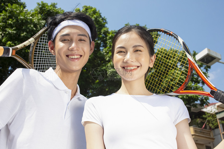 在户外网球场打网球的年轻情侣图片