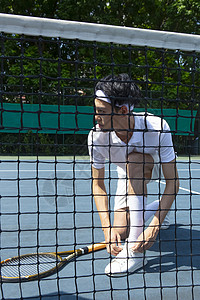 在网球场系鞋带的网球教练图片