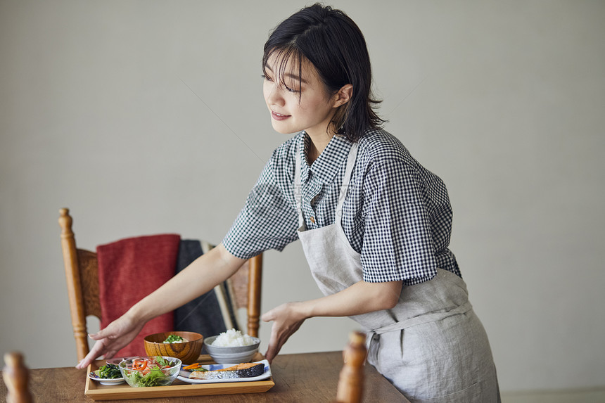 青年女子将餐盘放在桌上图片