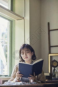 窗边阅读的年轻女子图片