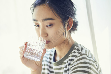 窗户旁喝水的女人图片