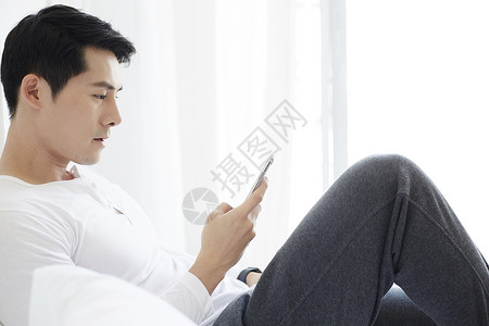 倚在沙发上看手机的男士图片