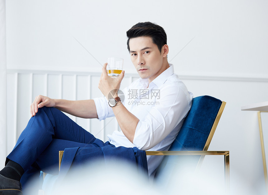 坐在椅子上喝酒的男士图片