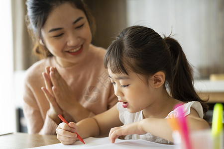 年轻妈妈陪伴女儿绘画图片