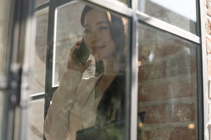 窗边接听电话的青年女子图片