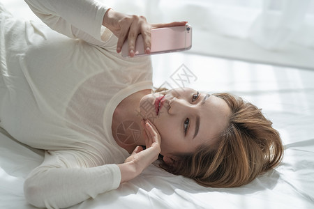 躺在床上看手机的青年女子图片