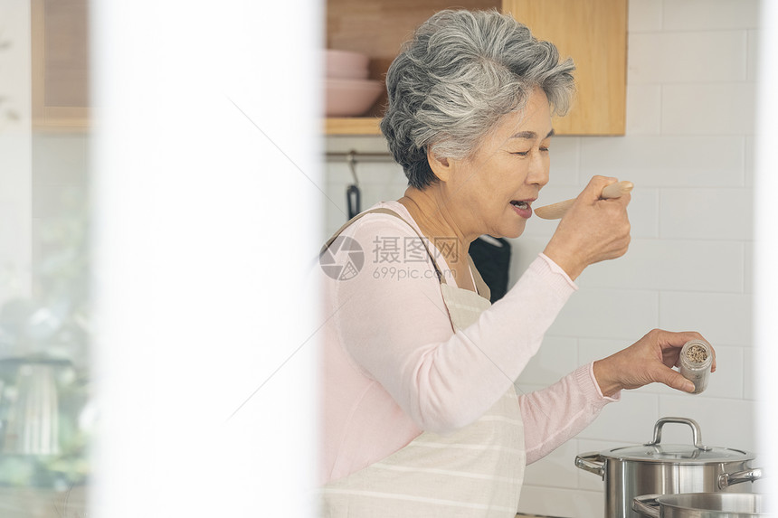 厨房里做饭品尝的老年女性图片