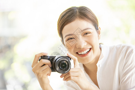 拿着相机开心微笑的年轻女子图片