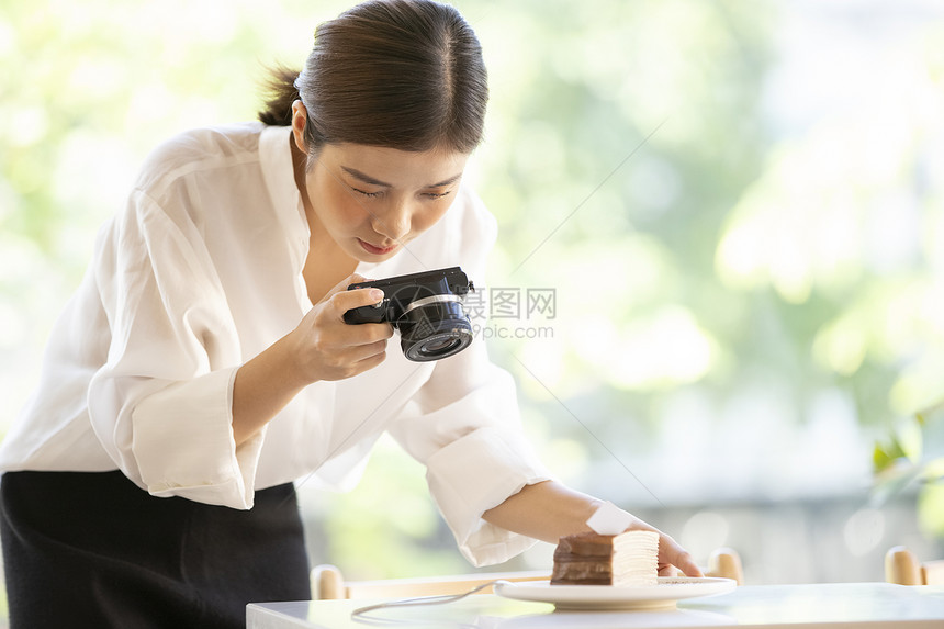 相机拍摄食物照片的年轻女子图片