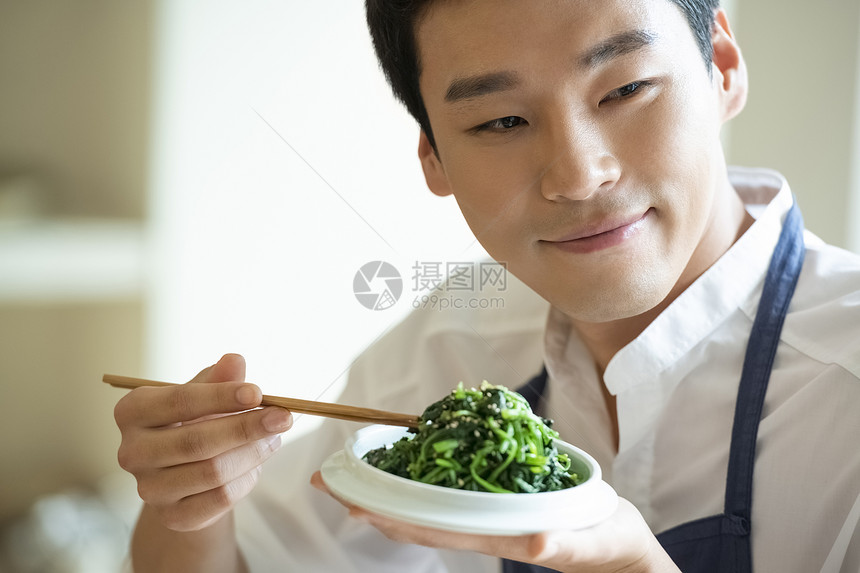 手拿筷子品尝餐点的厨师图片