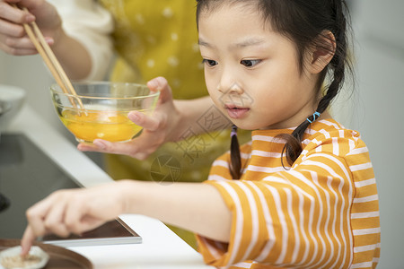 厨房帮助妈妈制作料理的小女孩图片