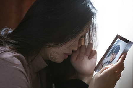 年轻女子看着照片孤独流泪高清图片