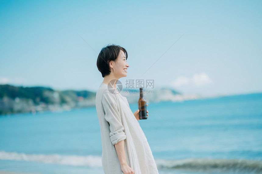 海滩上喝酒的青年女子图片