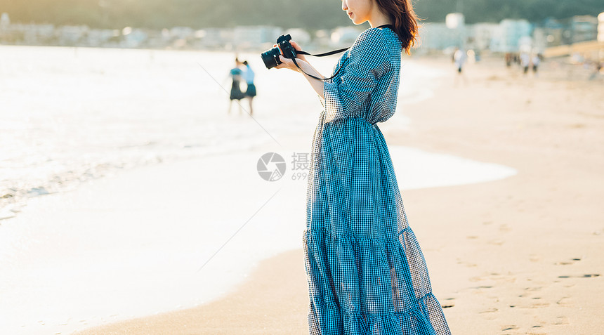 海边拿着相机的年轻女子特写图片