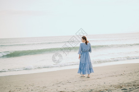 夹趾凉拖海滩上漫步的年轻女子背景