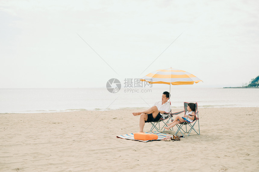 坐在海滩上看风景的父女图片