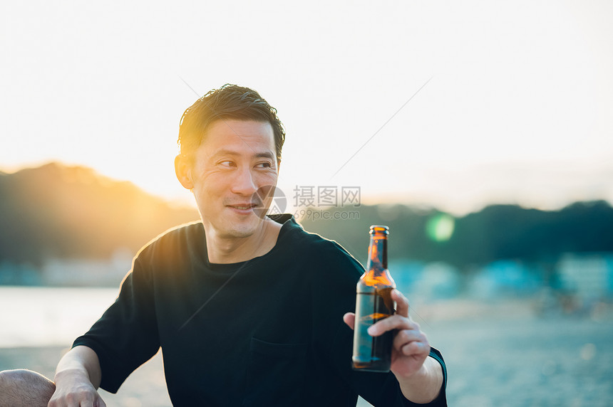 海滩上拿着啤酒的成年男子图片