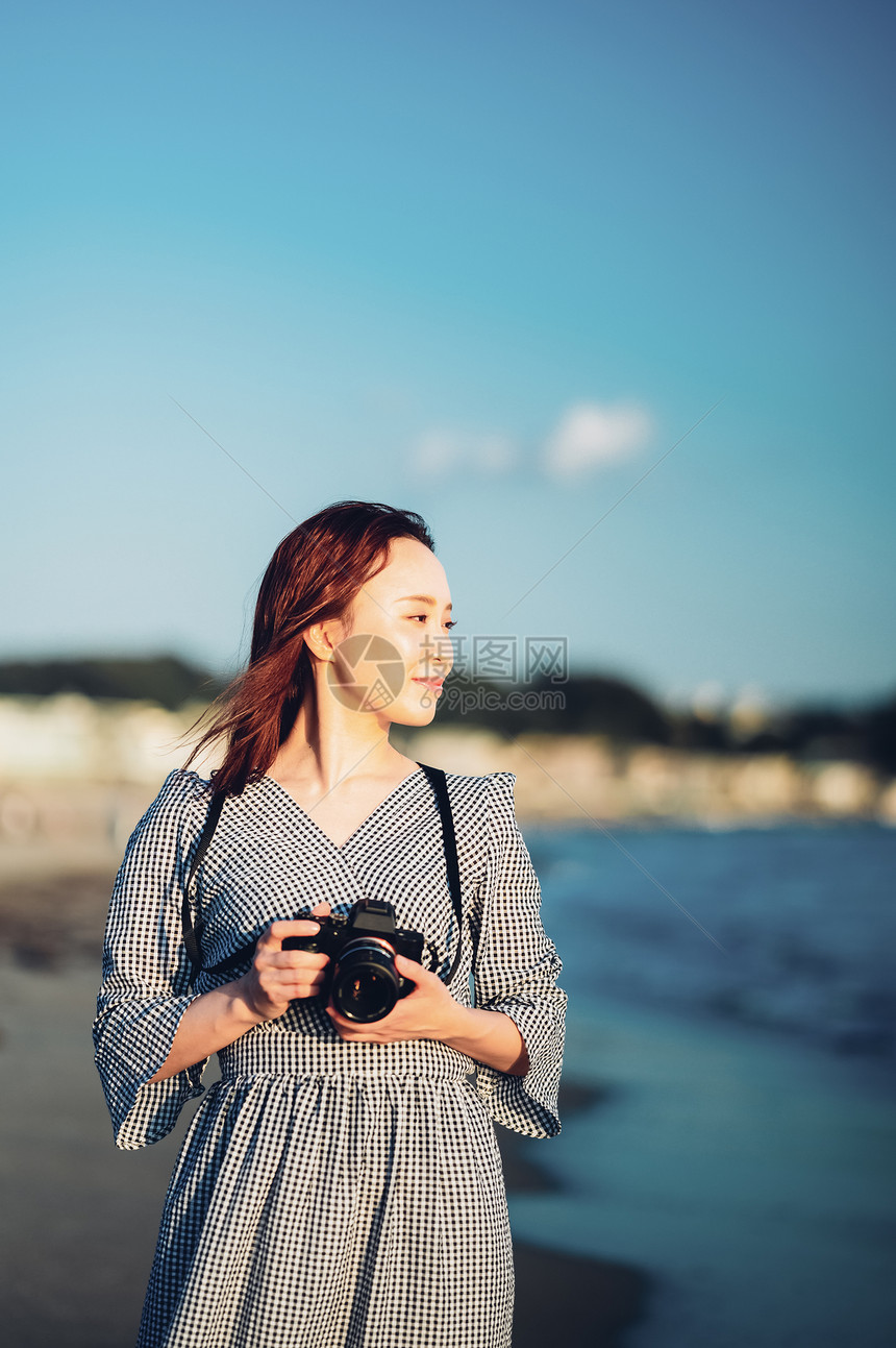 海边拿着相机的年轻女子图片