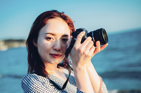 海边拿着相机的年轻女子图片