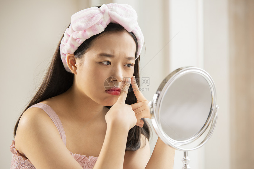 年轻女性照化妆镜子挤脸上的痘痘图片