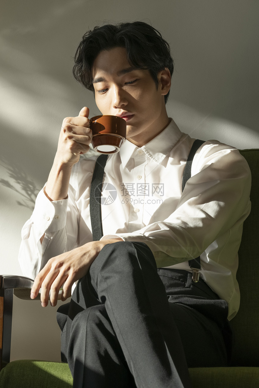 年轻男人坐在沙发里喝咖啡图片