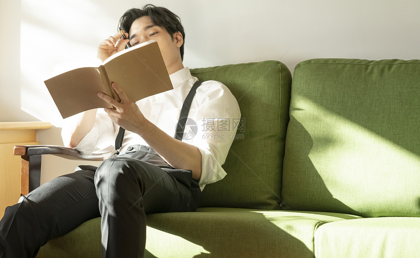 年轻男人坐在沙发里看书图片