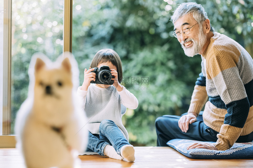 孙女用相机给狗狗拍照图片
