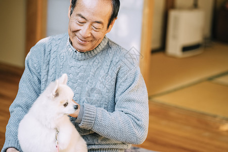 正圆抱着博美犬的老人背景