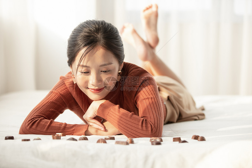 看着巧克力微笑的年轻女子图片