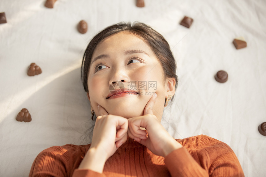 躺在巧克力堆里开心的年轻女子图片