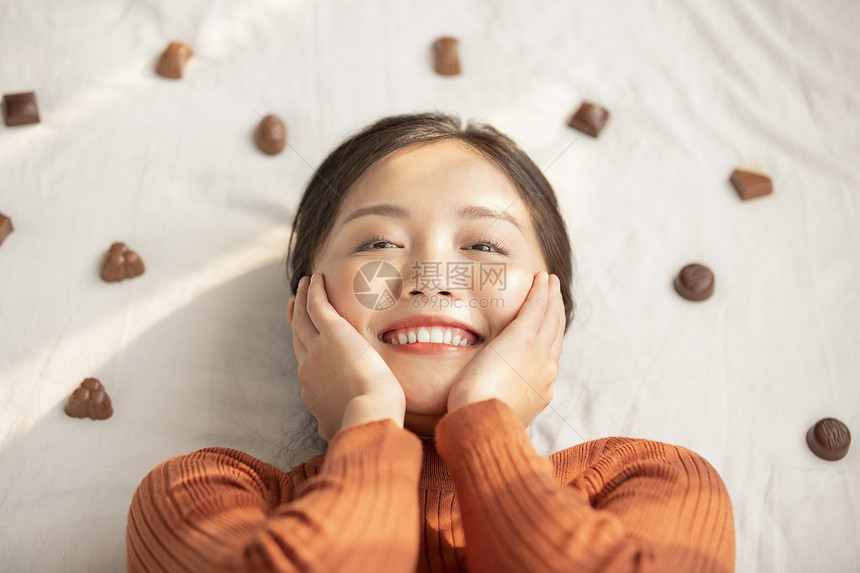 青春毛衣二十多岁躺着用巧克力的年轻女子图片