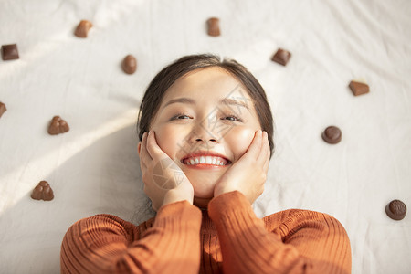 青春毛衣二十多岁躺着用巧克力的年轻女子图片
