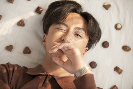 展示美颜绝妙的躺着用巧克力的年轻人图片