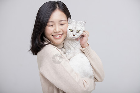 微笑模特抚养猫拥抱女人灰色背景画像图片