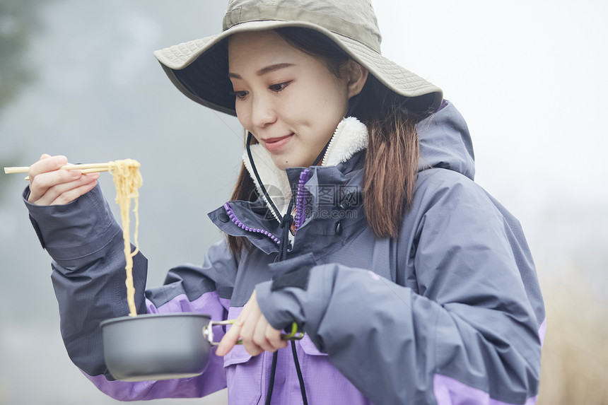 年轻女人徒步登山探险吃泡面图片