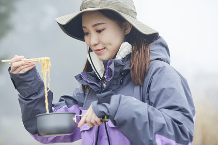 年轻女人徒步登山探险吃泡面图片