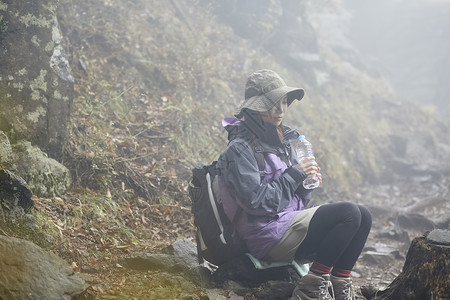 山上休息喝水的徒步女青年图片