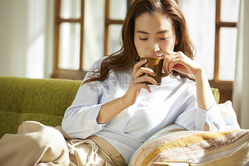 沙发上喝咖啡休息的青年女子图片