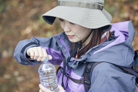 森林里徒步休息喝水的青年女性图片