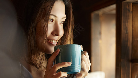 居家拿着咖啡微笑的年轻女子图片
