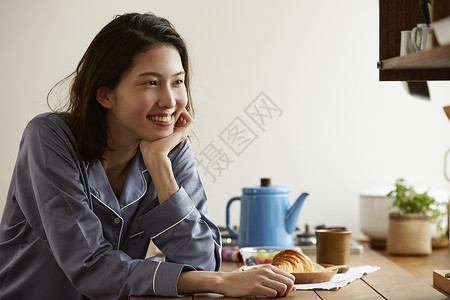 居家穿着睡衣吃早餐微笑的女青年图片