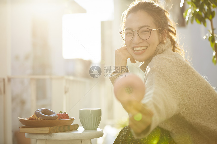 拿着甜甜圈开心微笑的年轻女子图片