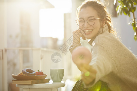 拿着甜甜圈开心微笑的年轻女子图片