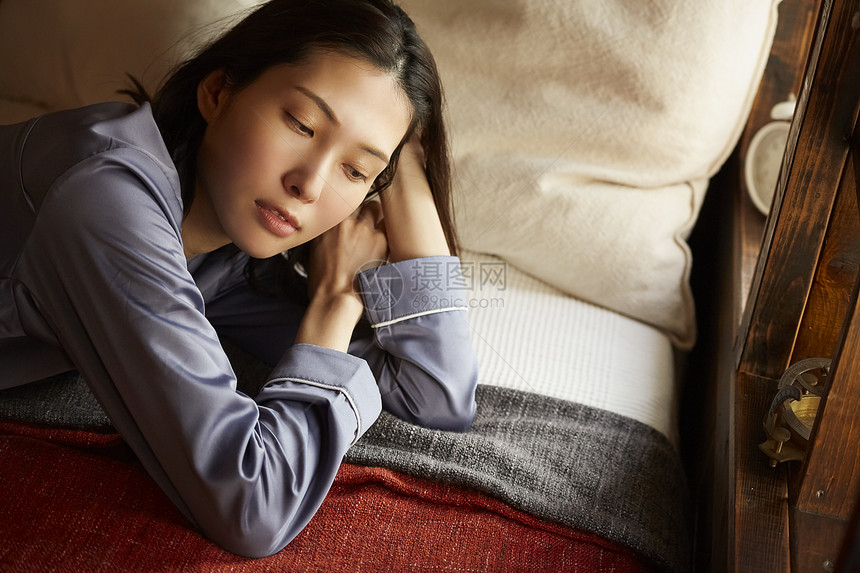 躺在卧室床上休息的青年女子图片