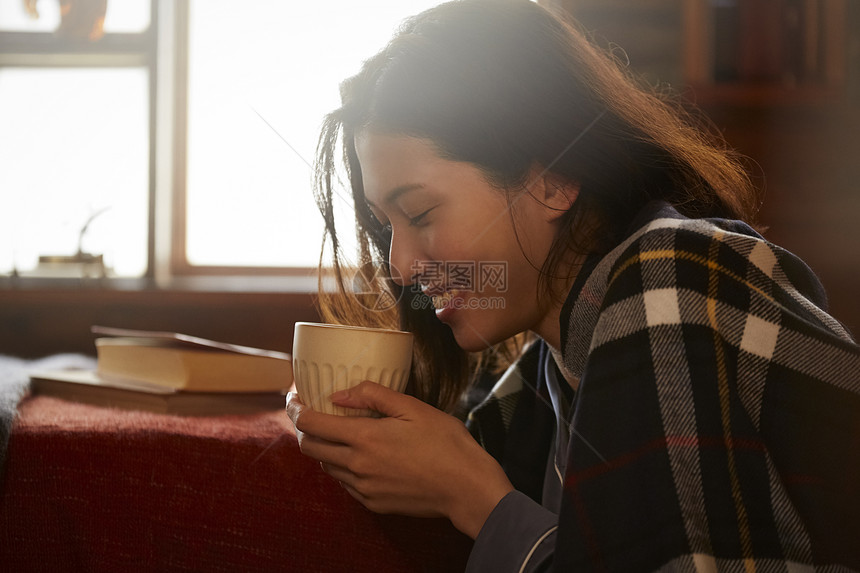 卧室里捧着咖啡的年轻女子图片