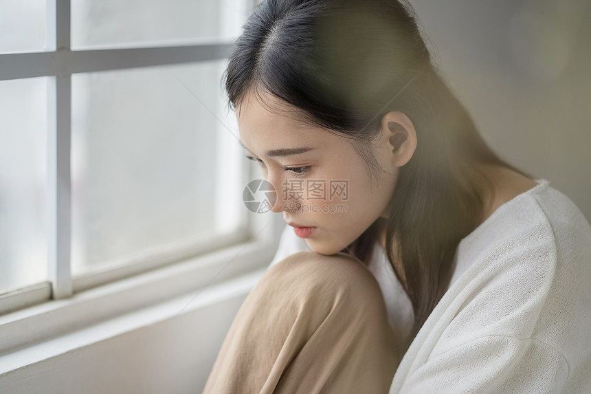 窗边忧郁沉思的年轻女子图片