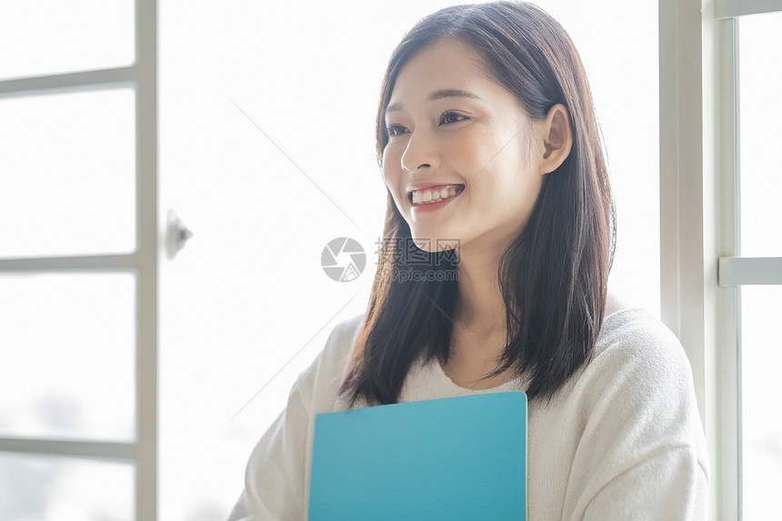 抱着文件夹微笑的青年商务女性图片