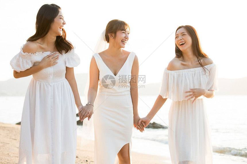 海滩上散步的新娘和朋友图片