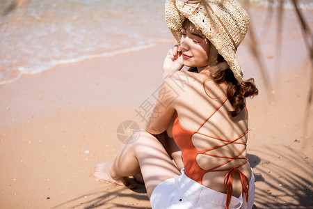 夏天日光泳衣泳装的一名妇女坐在海滩图片