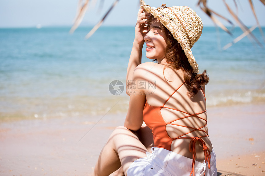 有趣白人盥洗用品泳装的一名妇女坐在海滩图片